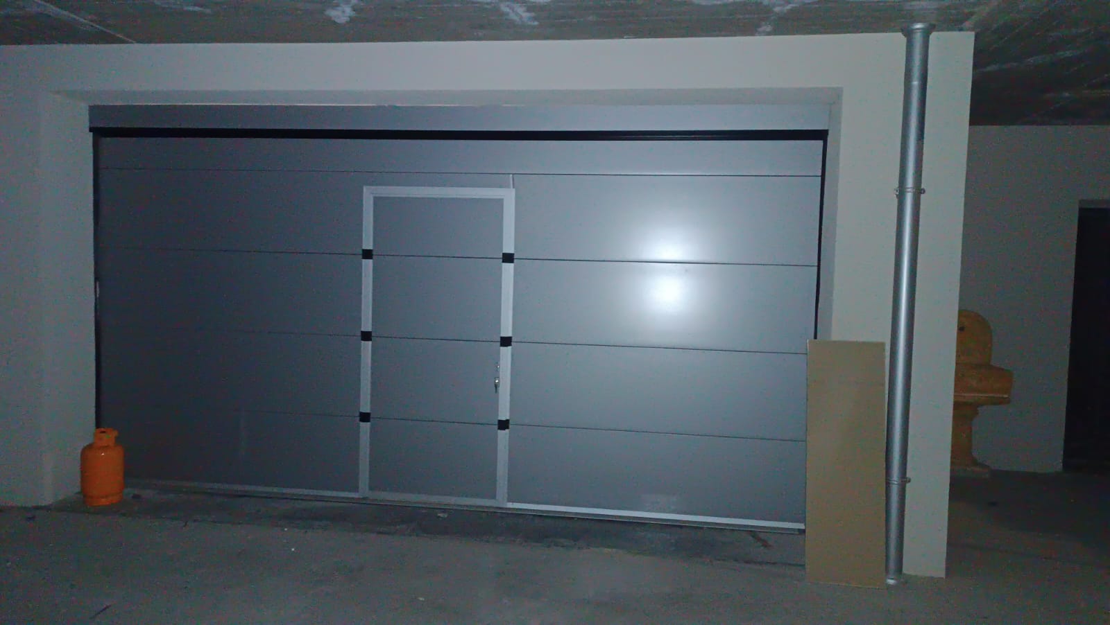 porta sezionale a <p>porta sezionale oltre luce, con portina inserita e pannello intero. RAL 9006</p>