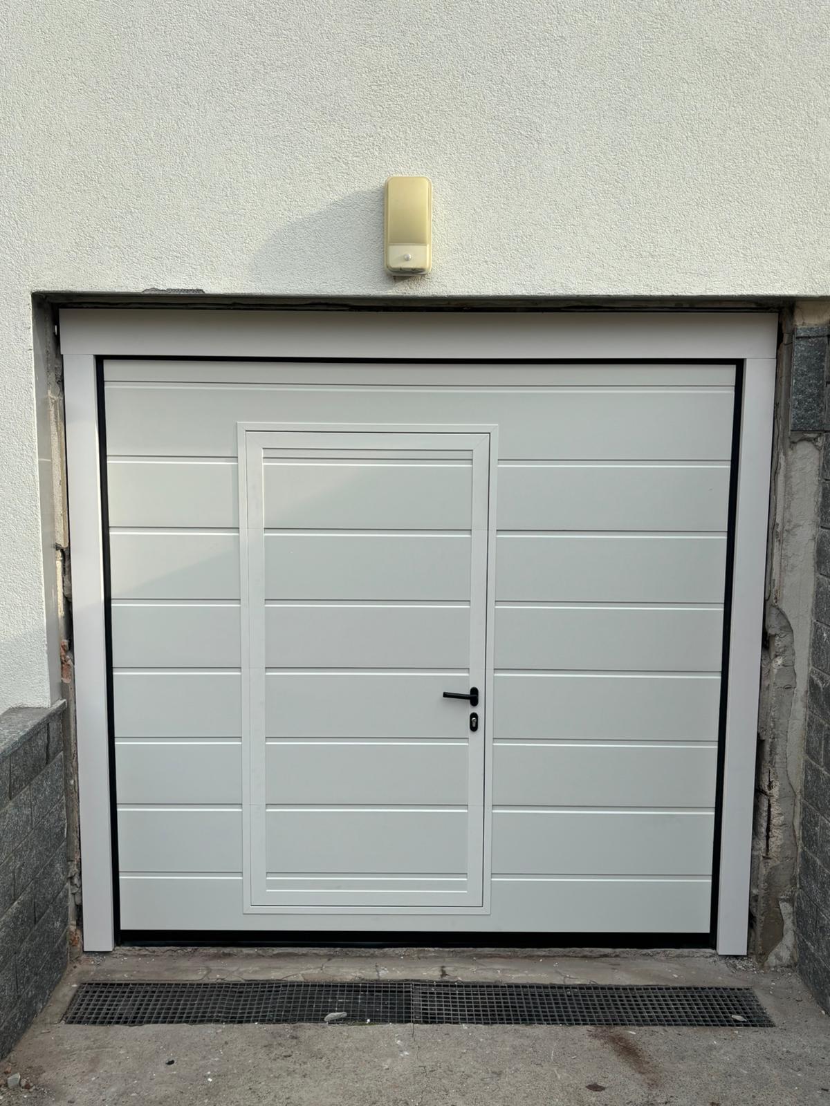 porta sezionale a <p>port sezionale in luce, con portina inserita e panello con doga da 25cm. RAL 9010</p>