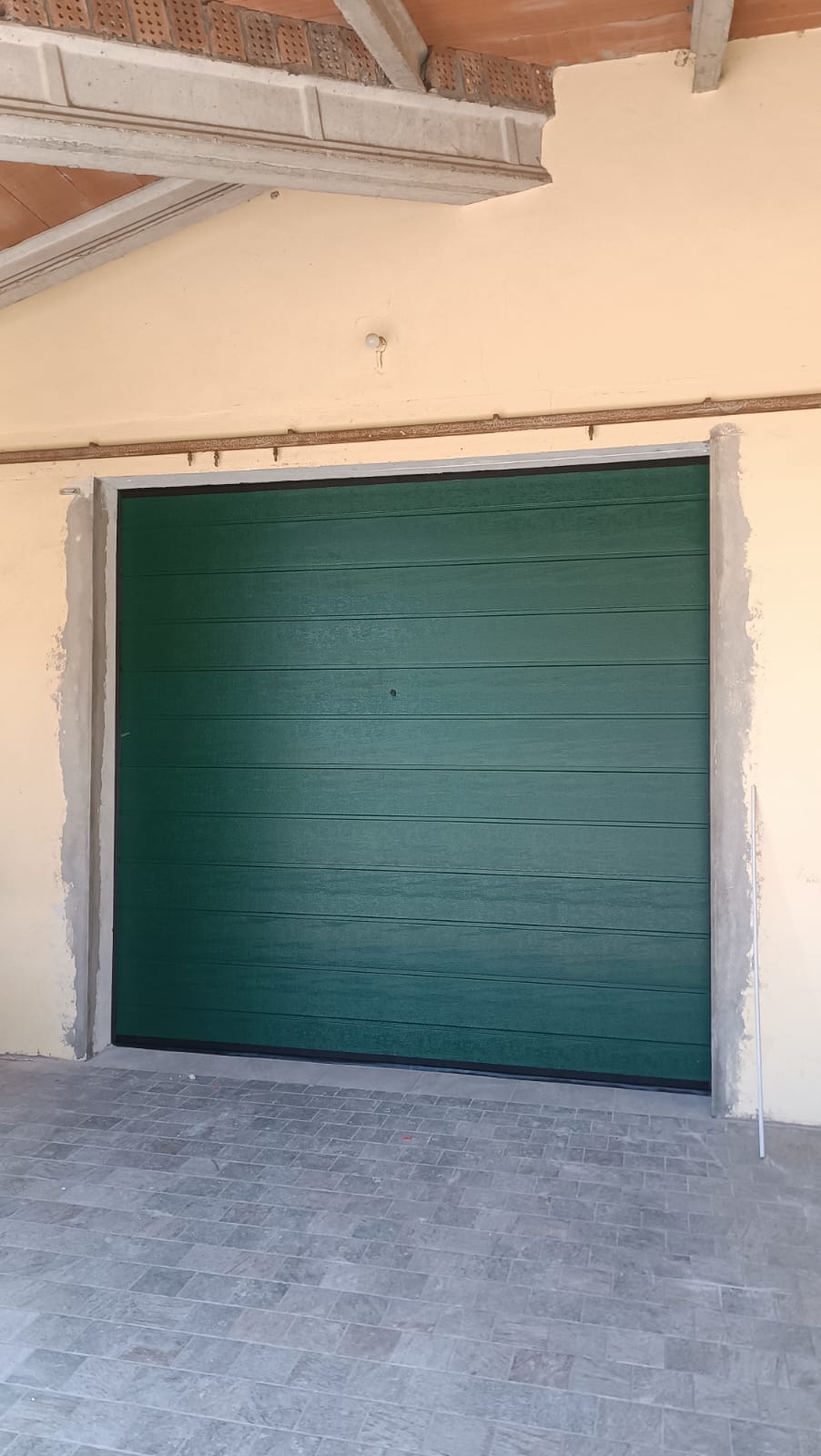 porta sezionale a <p>porta sezionale oltre luce, con sblocco esterno e pannello con doga da 25cm. RAL 6005</p>