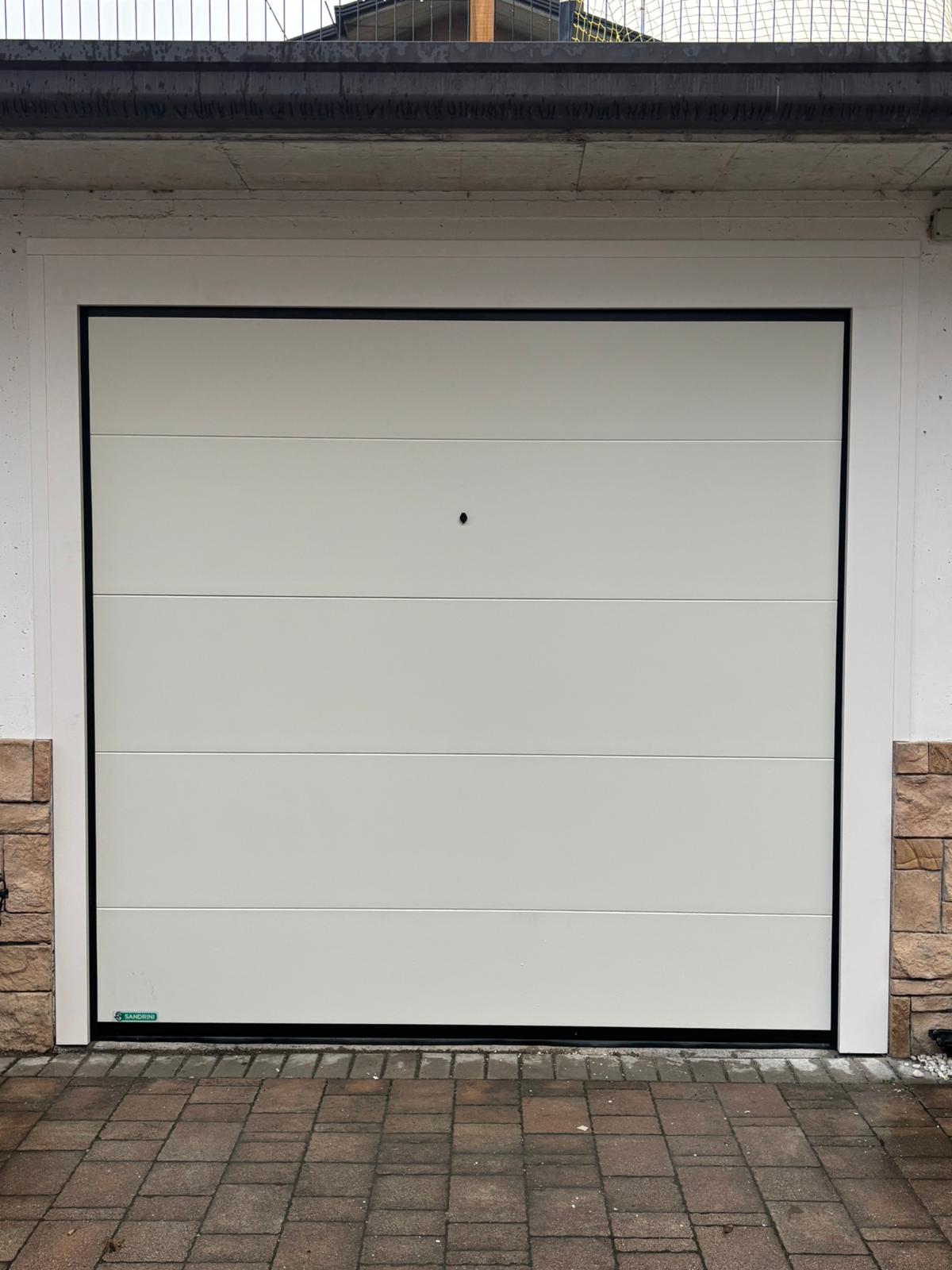 porta sezionale a <p>porta sezionale in luce, con coprifili, sblocco esterno e pannello intero. RAL 9010</p>