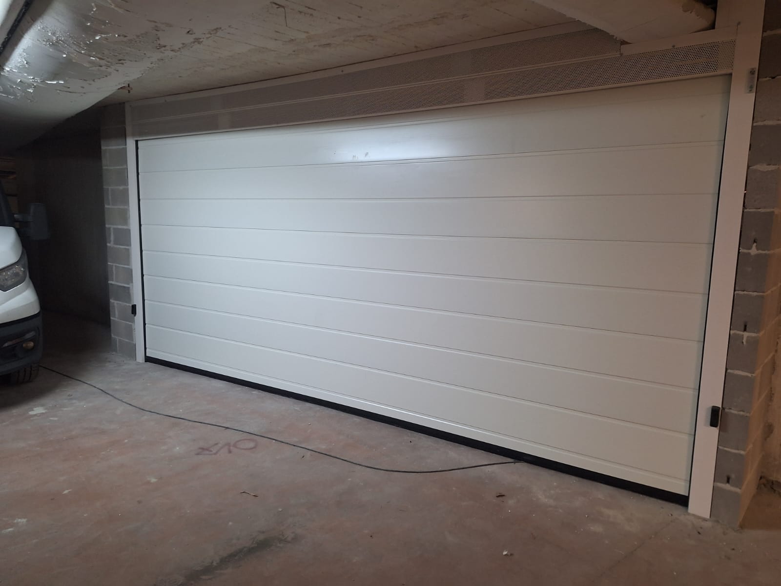 porta sezionale a <p>porta sezionale in luce, con veletta areata, lampeggiante, fotocellule e pannello con doga da 25cm. RAL 9010</p>