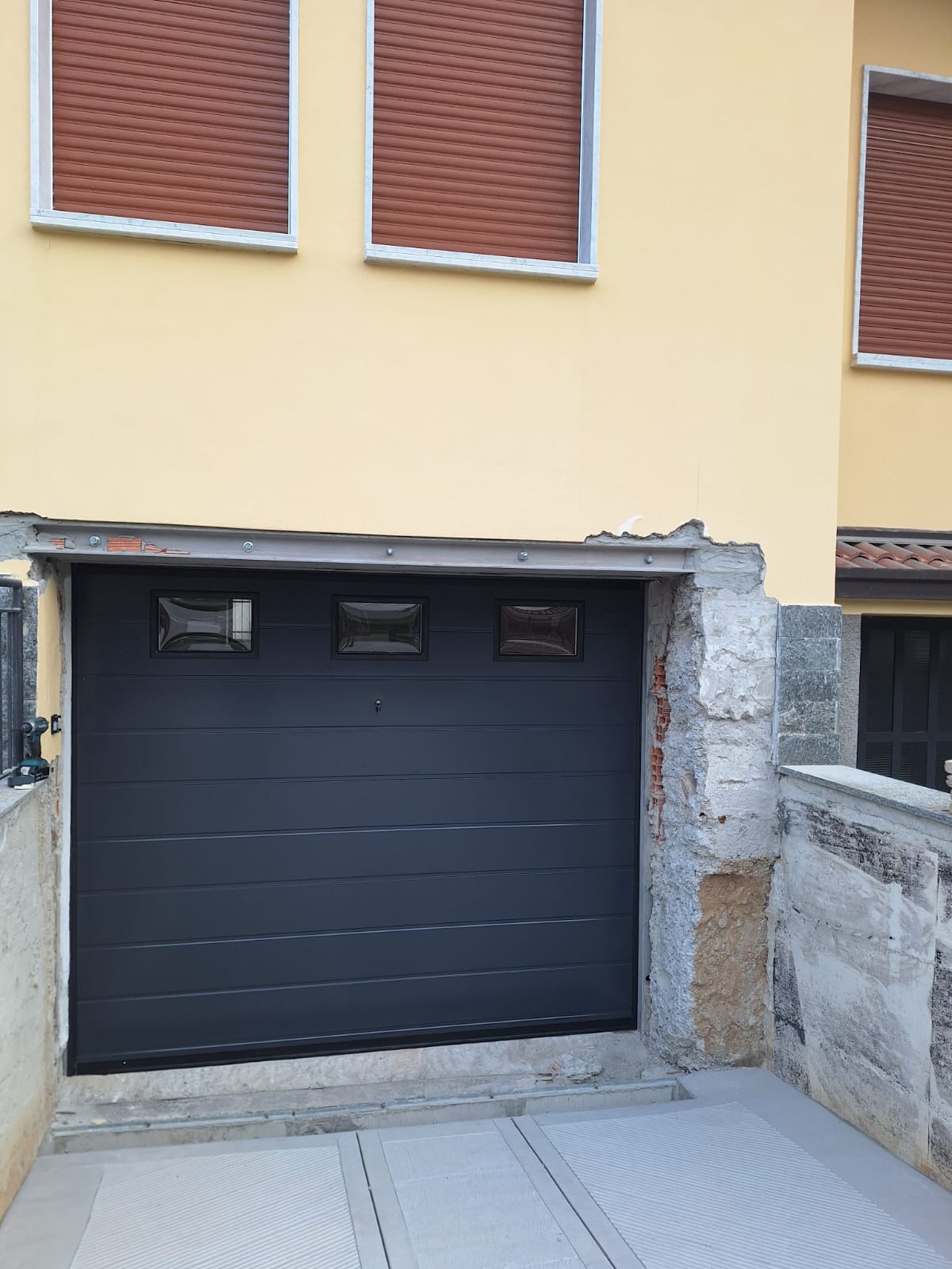 porta sezionale a <p>porta sezionale oltre luce, con oblò, sblocco esterno e pannello con doga da 25cm. RAL 7016 </p>