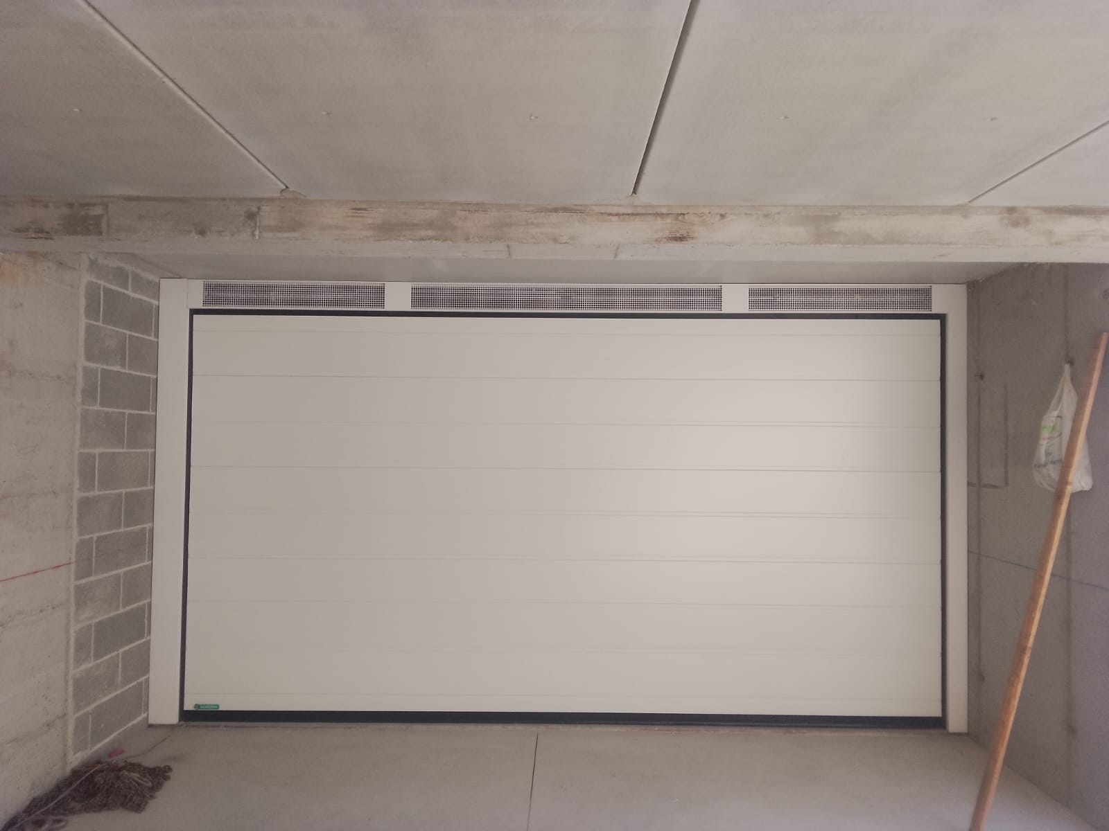 porta sezionale a <p>cantiere di porte sezionali in luce, con veletta areata e pannello con doga da 25cm. RAL 9010</p>