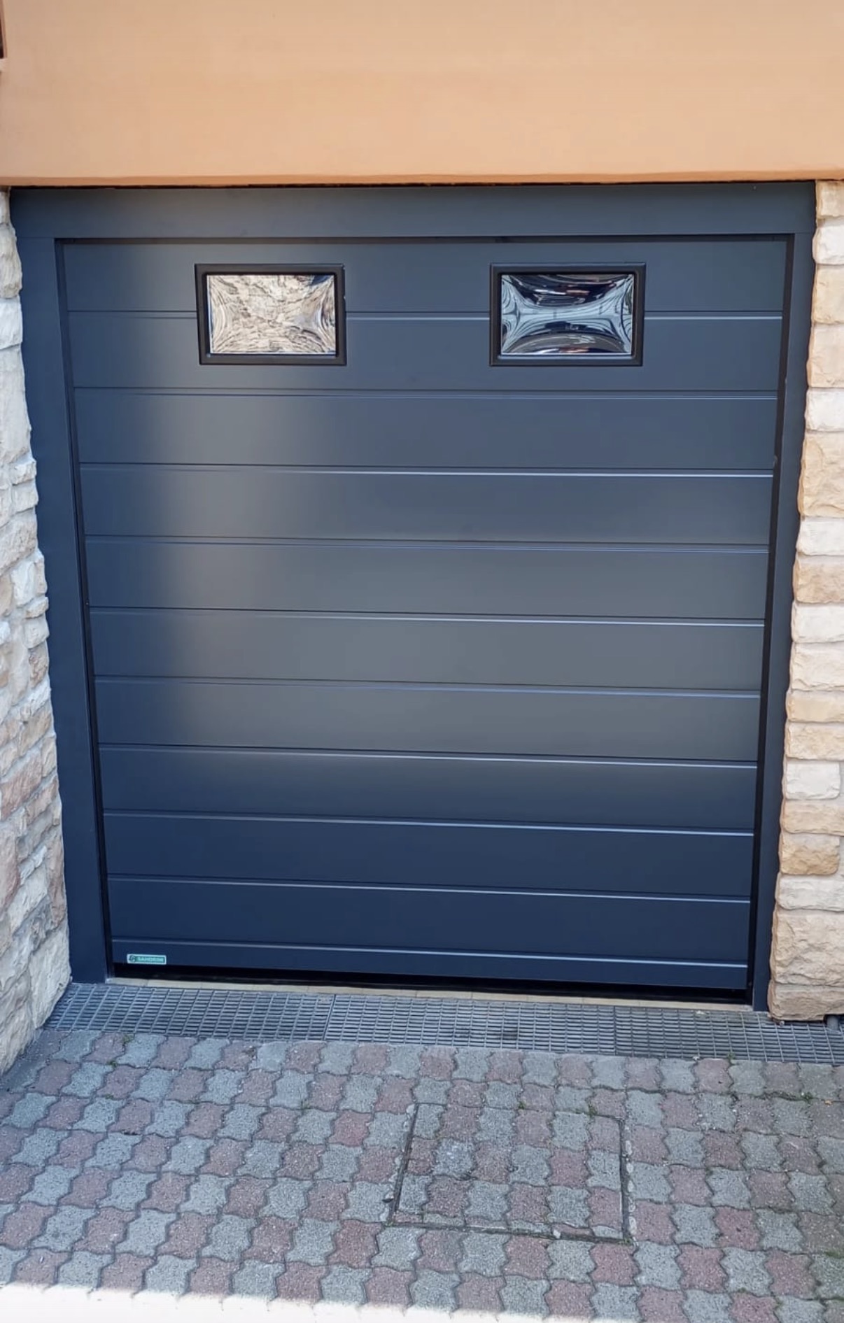 porta sezionale a <p>porta sezionale in luce, con oblò e pannello con doga da 25cm. RAL 7016</p>