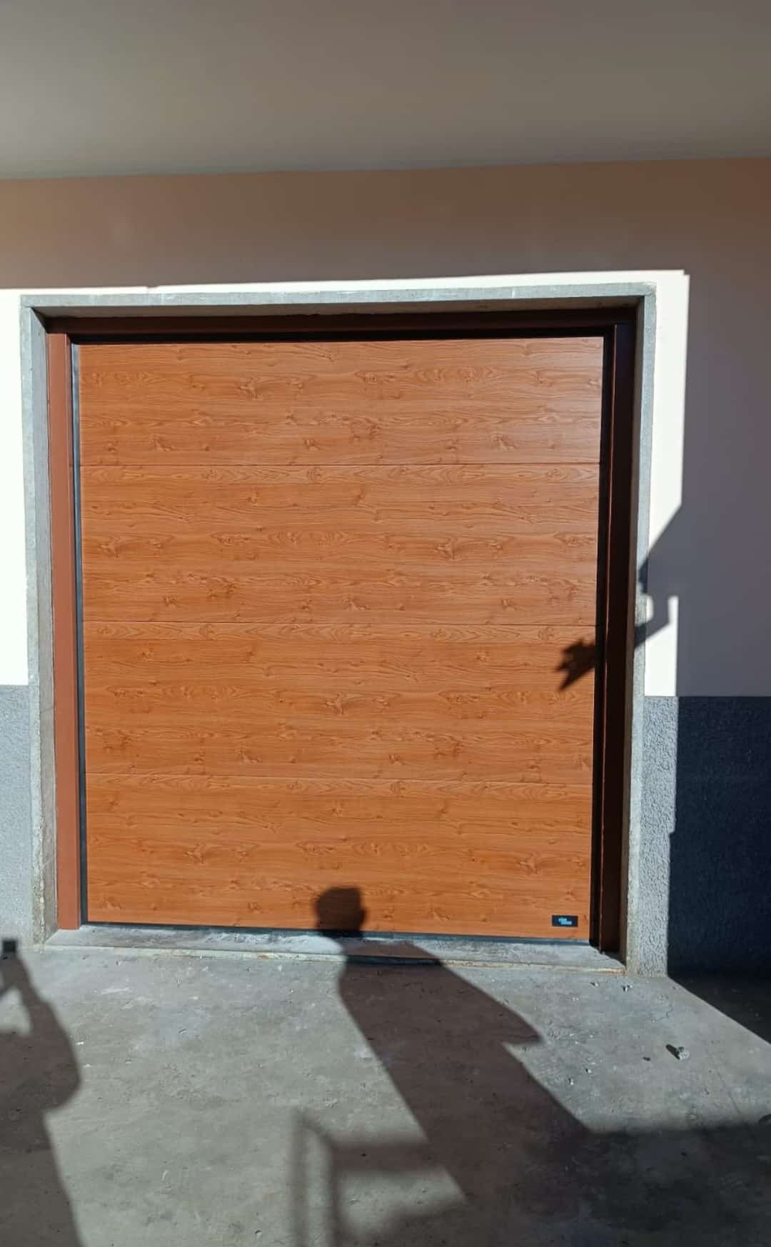 Porta sezionale a <p>Porta sezionale in luce, con maniglia di sollevamento e pannello intero. Colore effetto legno </p>