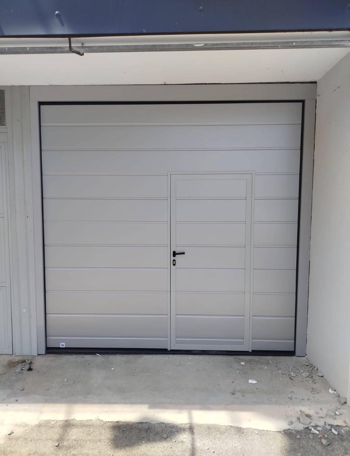 porta sezionale a <p>porta sezionale in luce, con portina inserita e pannello con doga da 25cm. RAL 9006</p>