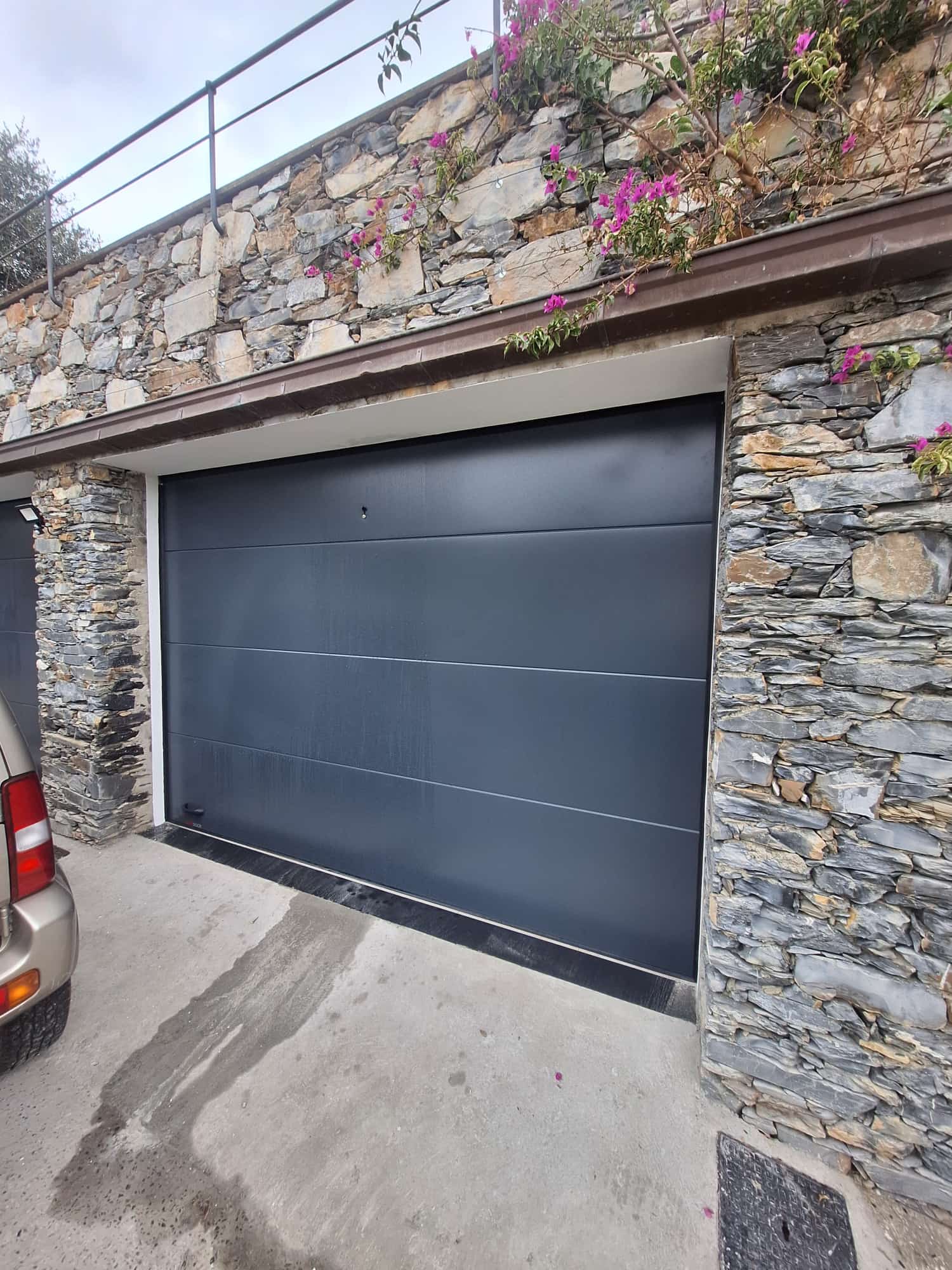 porta sezionale a <p>porta sezionale oltre luce, con sblocco esterno, maniglia di sollevamento e pannello intero. RAL 7016</p>