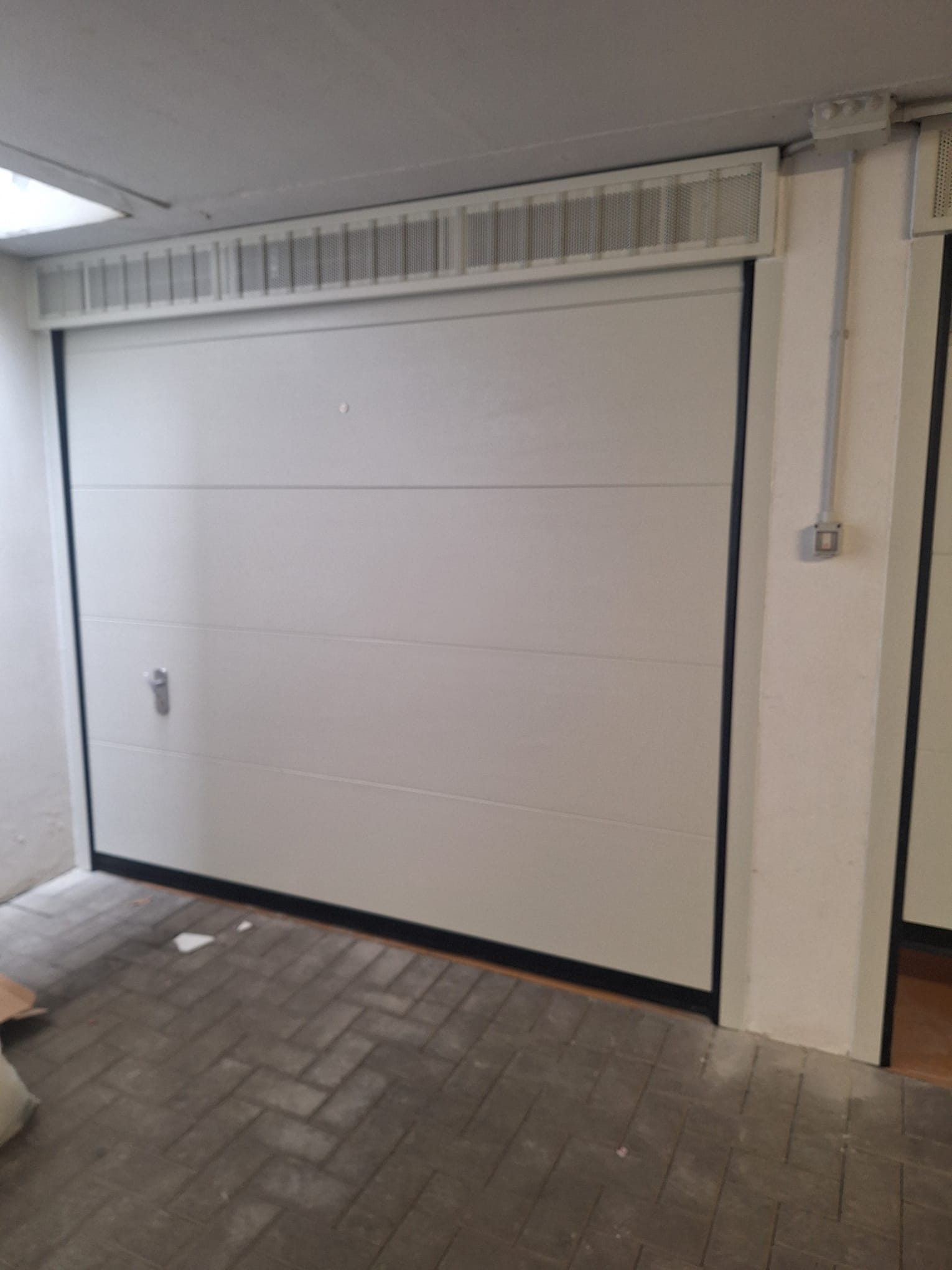 porta sezionale a <p>porta sezionale in luce, con veletta areata, sblocco esterno e pannello intero. RAL 9010</p>