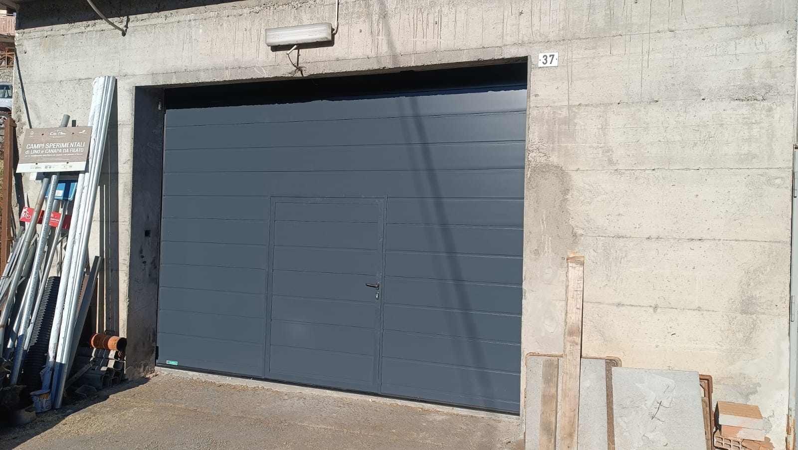 porta sezionale a <p>porta sezionale oltre luce, con portina inserita, lampeggiante e pannello con doga da 25cm. RAL 7016</p>