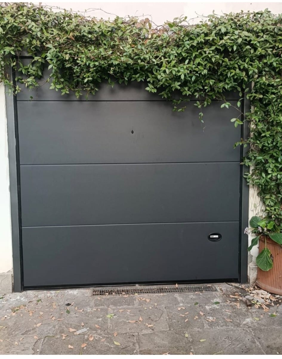 porta sezionale a <p>porta sezionale in luce, con maniglia di sollevamento, sblocco esterno e pannello intero; porta tagliafuoco ad anta singola e maniglia su entrambi i lati. RAL 7016</p>