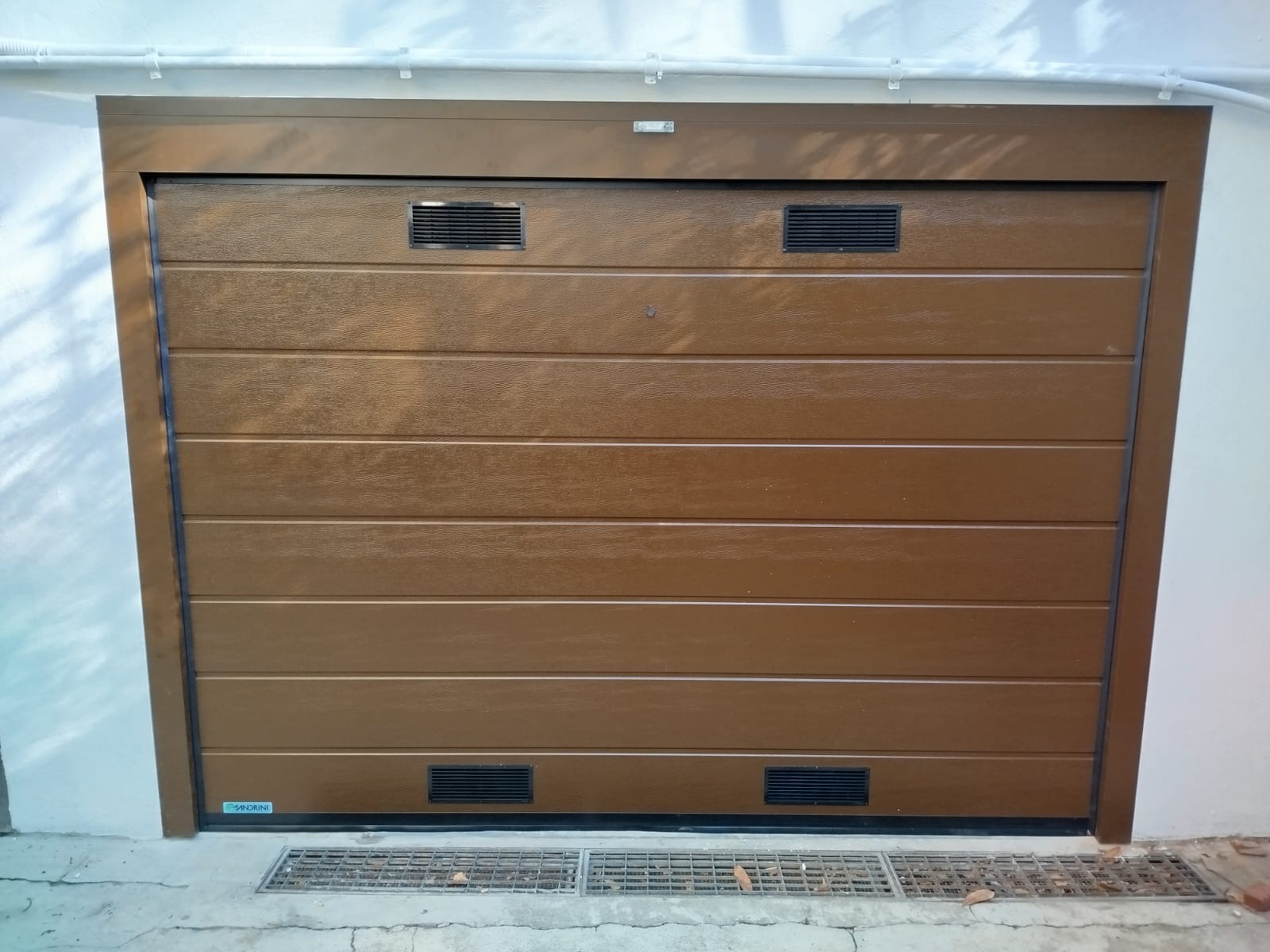 Porta sezionale a <p>Porta sezionale in luce, con coprifili, lampeggiante, griglie di areazione, sblocco esterno e pannello con doga da 25cm. Colore effetto legno </p>