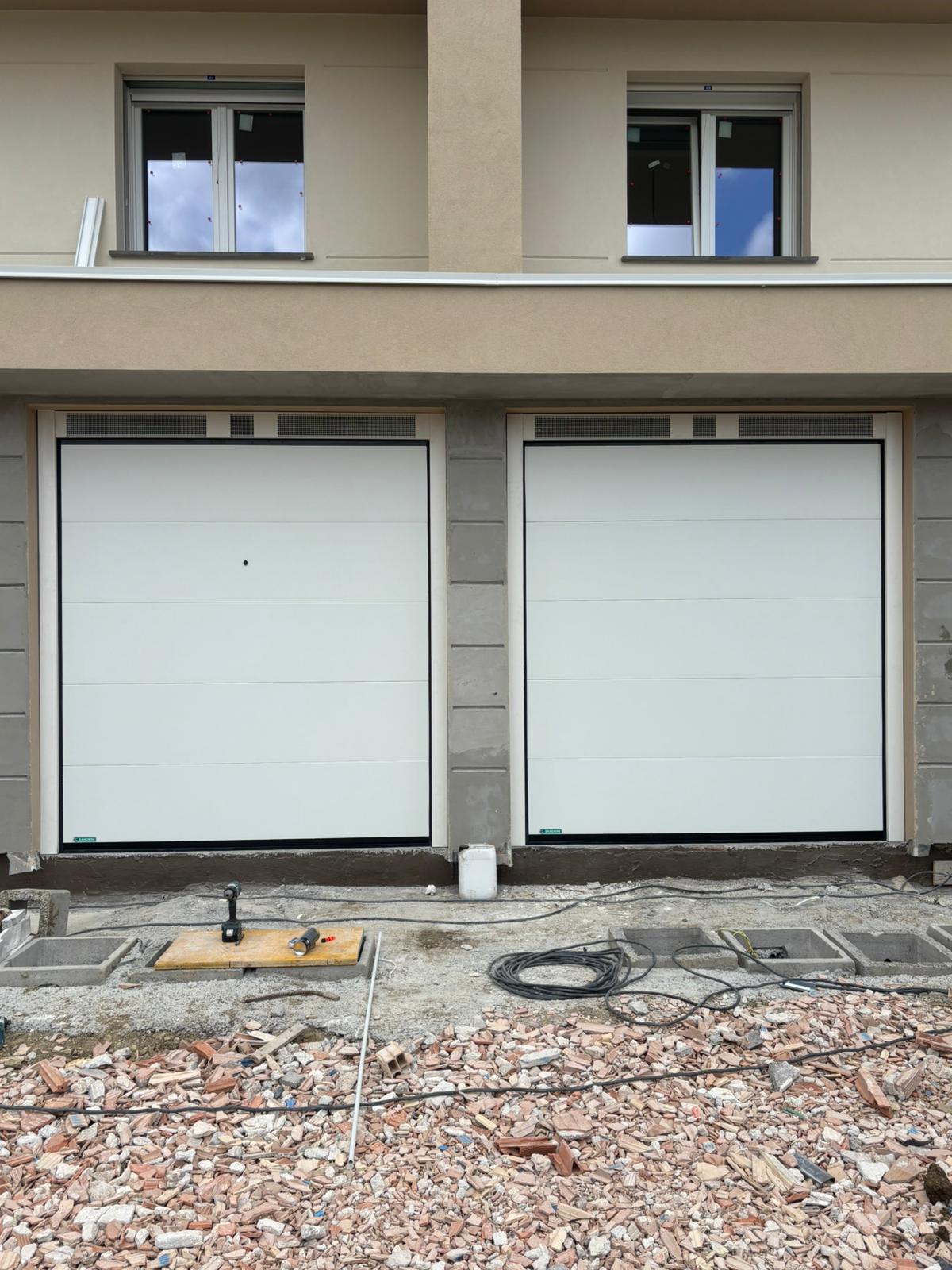 porta sezionale a <p>porta sezionale in luce, con veletta areata, sblocco esterno e pannello intero. RAL 9010</p>