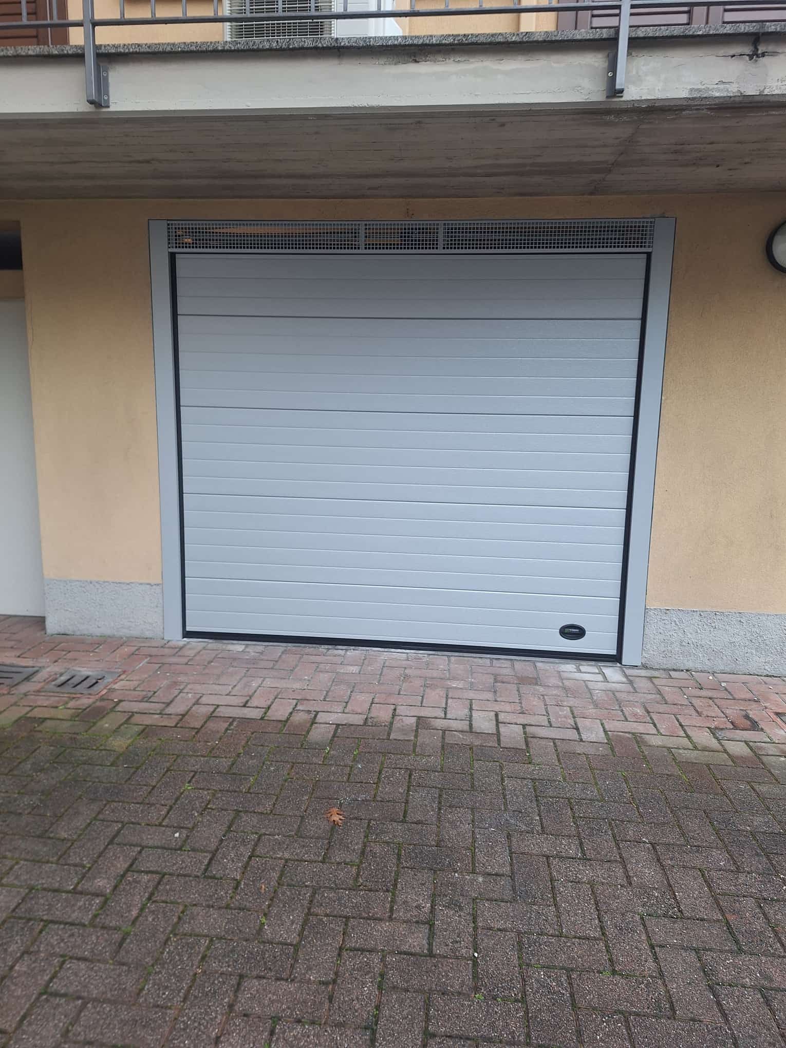 porta sezionale a <p>porta sezionale in luce, con veletta areata, maniglia di sollevamento, sblocco esterno e pannello con doga da 10cm. RAL 7035</p>