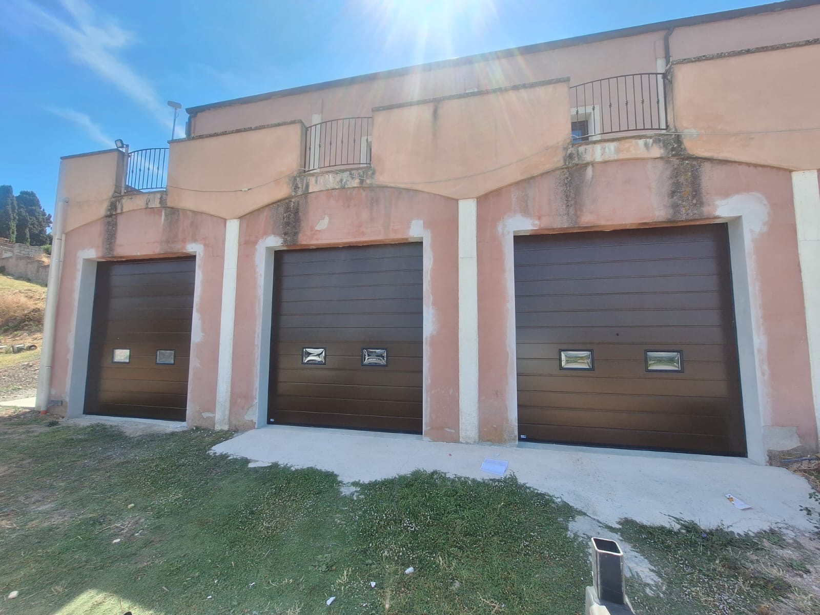 Porta sezionale a <p>Porta sezionale oltre luce, con oblò, sblocco esterno e pannello con doga da 25cm. RAL 8014</p>
