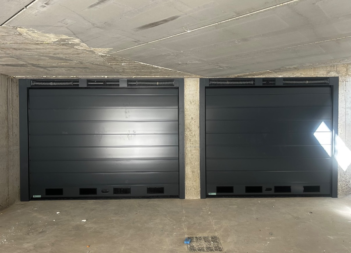 porta sezionale a <p>porte sezionali in luce, con veletta areata, griglie di areazione e pannello con doga da 25cm. RAL 7016</p>