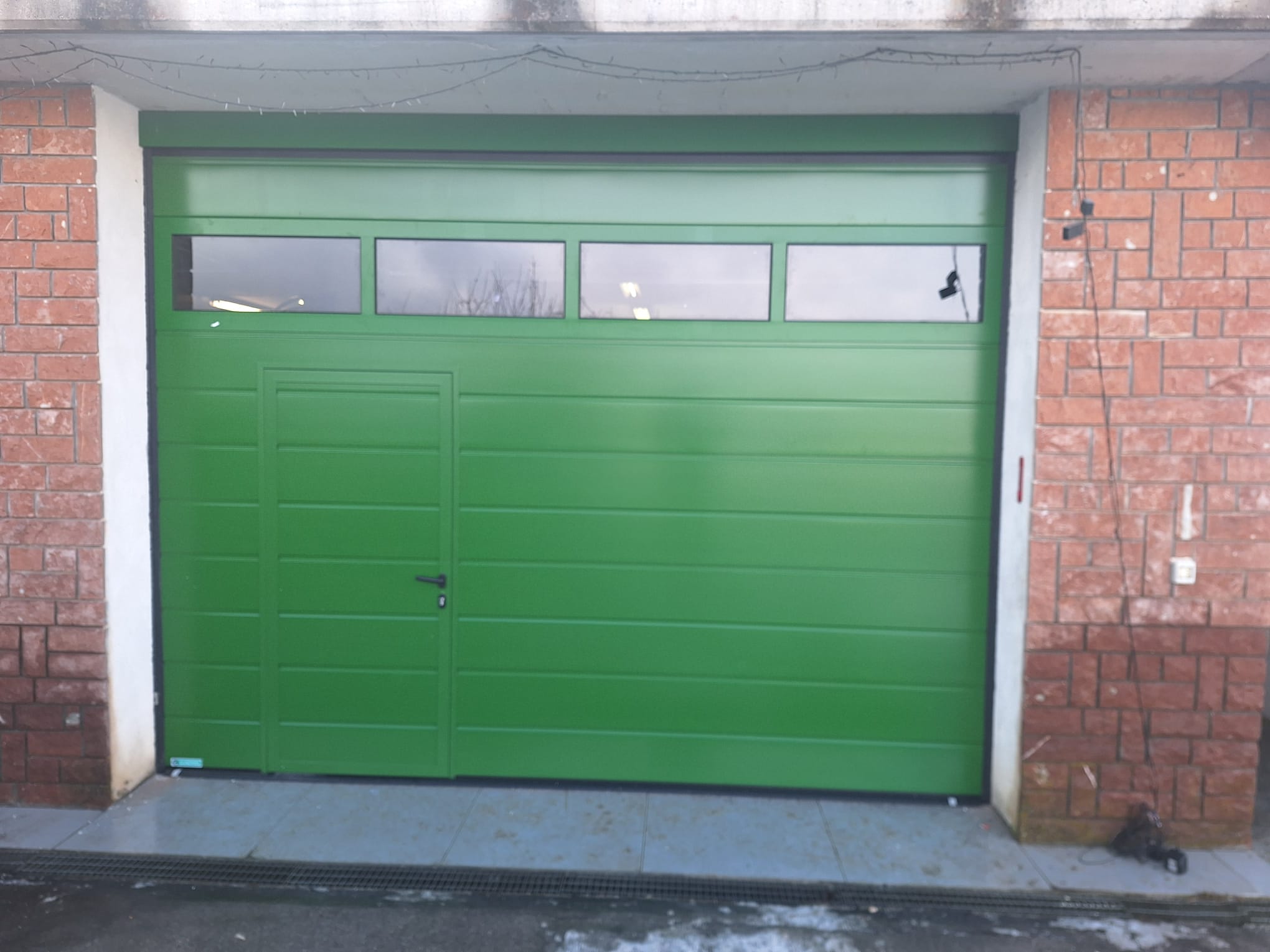 porta sezionale a <p>porta sezionale oltre luce, con portina inserita, oblò e pannello con doga da 25cm. RAL a campione</p>