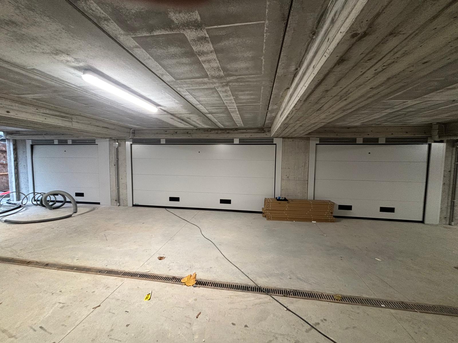 porta sezionale a <p>porta sezionale in luce, con veletta areata, griglie di areazione, sblocco esterno e pannello intero. RAL 9010</p>