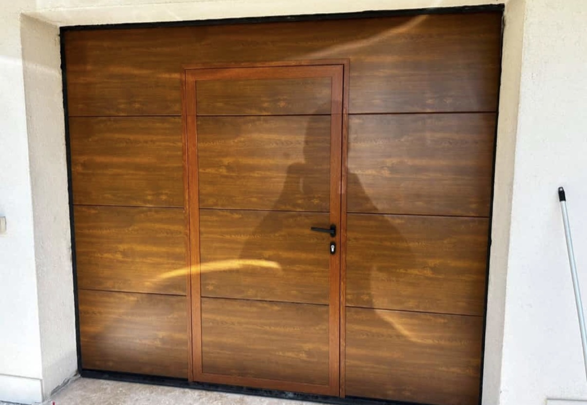 porta sezionale a <p>porta sezionale oltre luce, con portina inserita e pannello intero. Colore effetto legno </p>