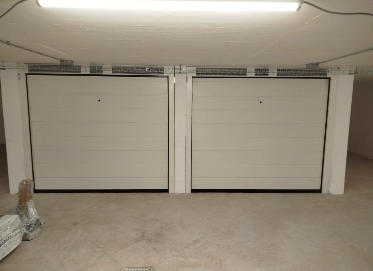 porta sezionale a <p>porta sezionale in luce, con veletta areata. sblocco esterno, lampeggiante e pannello con doga da 25cm. RAL 9010</p>