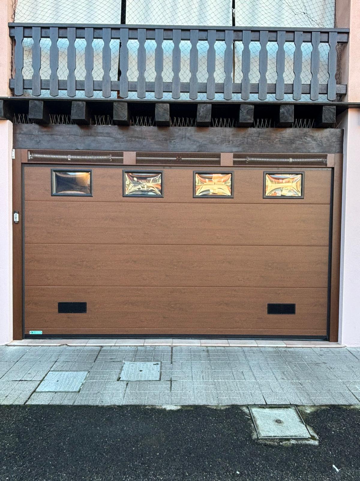 porta sezionale a <p>porta sezionale in luce, con veletta areata, oblò, griglie di areazione, lampeggiante, telecodi e pannello intero. Colore effetto legno</p>