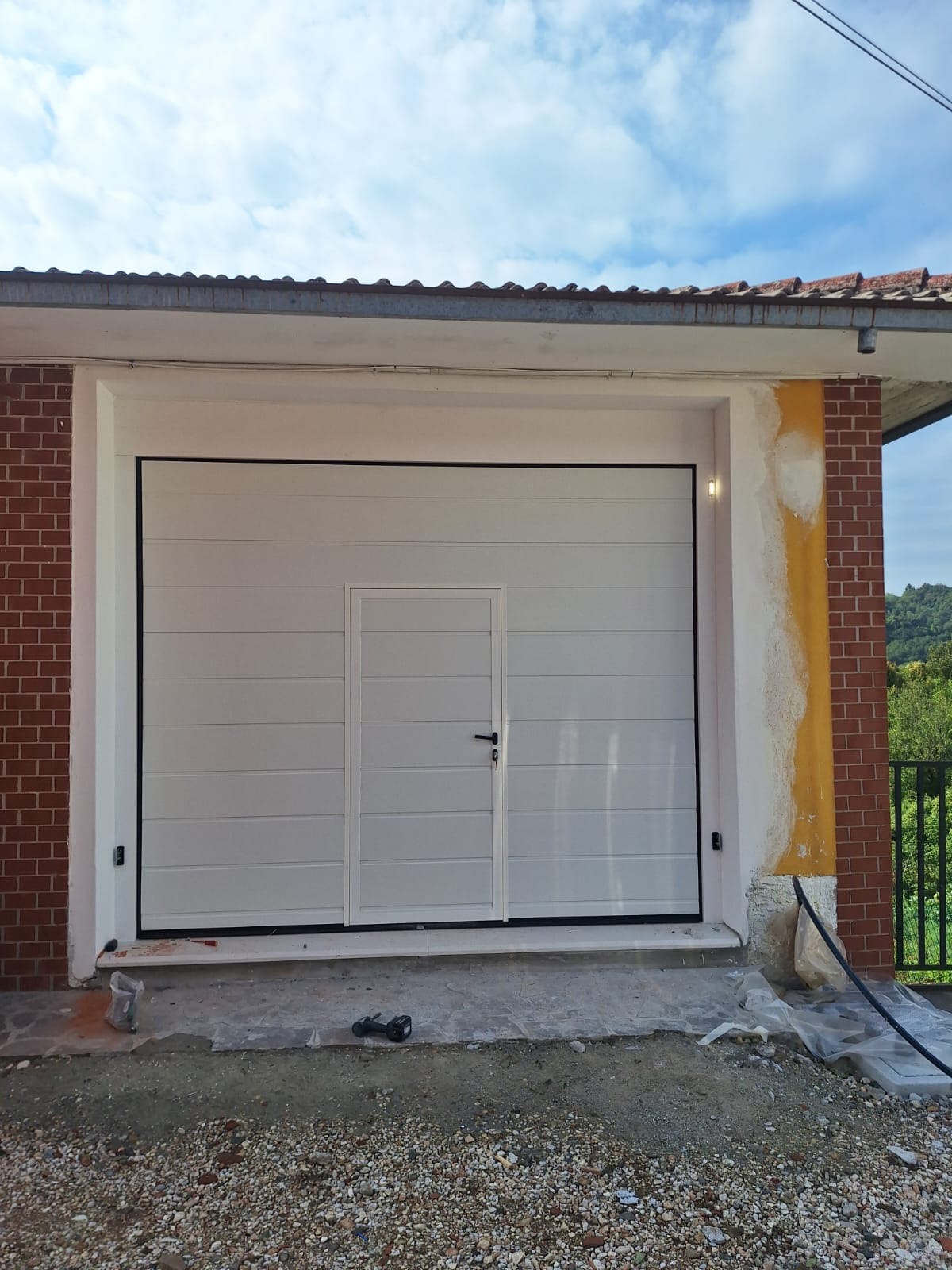 Porta sezionale a <p>Porta sezionale in luce, con fotocellule, lampeggiante, portina inserita e pannello con doga da 25cm. RAL 9010</p>