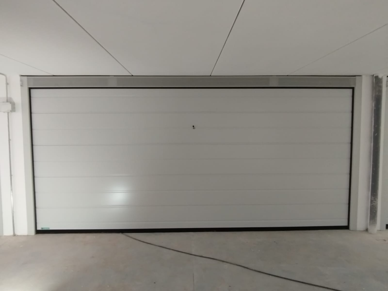 porta sezionale a <p>porta sezionale in luce, con veletta areata, sblocco esterno, lampeggiante e pannello con doga da 25cm. RAL 9010</p>