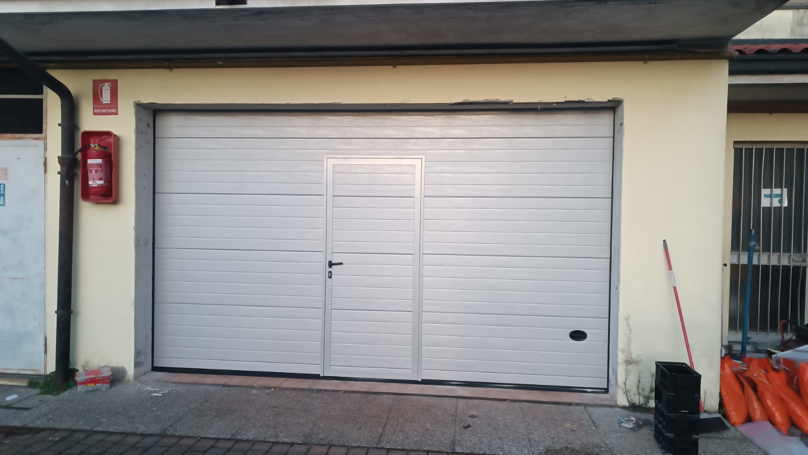 porta sezionale a <p>porta sezionale oltre luce, con maniglia di sollevamento, portina inserita e pannello con doga da 10cm. RAL 7035</p>