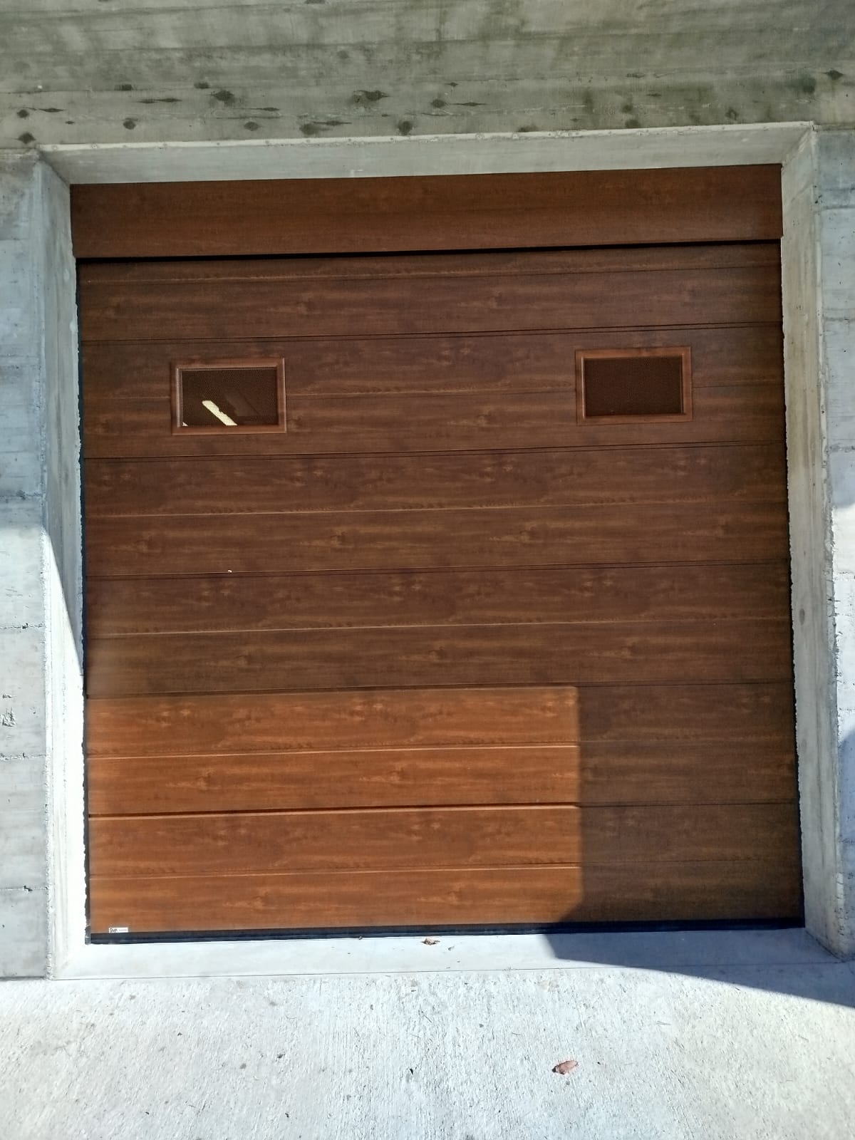 porta sezionale a <p>porta sezionale oltre luce, con tamponatura fissa, oblò e pannello con doga da 25cm. Colore effetto legno </p>