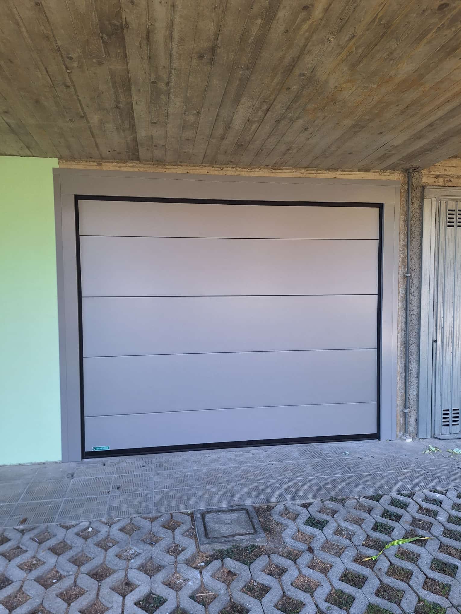 porta sezionale a <p>porta sezionale in luce, con coprifili e pannello intero. RAL 9006</p>