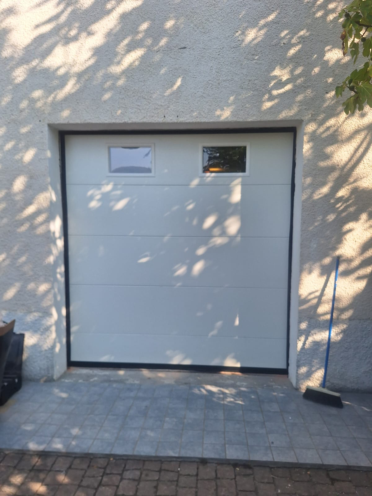 Porta sezionale a <p>Porta sezionale oltre luce, con oblò e pannello intero. RAL 9010</p>