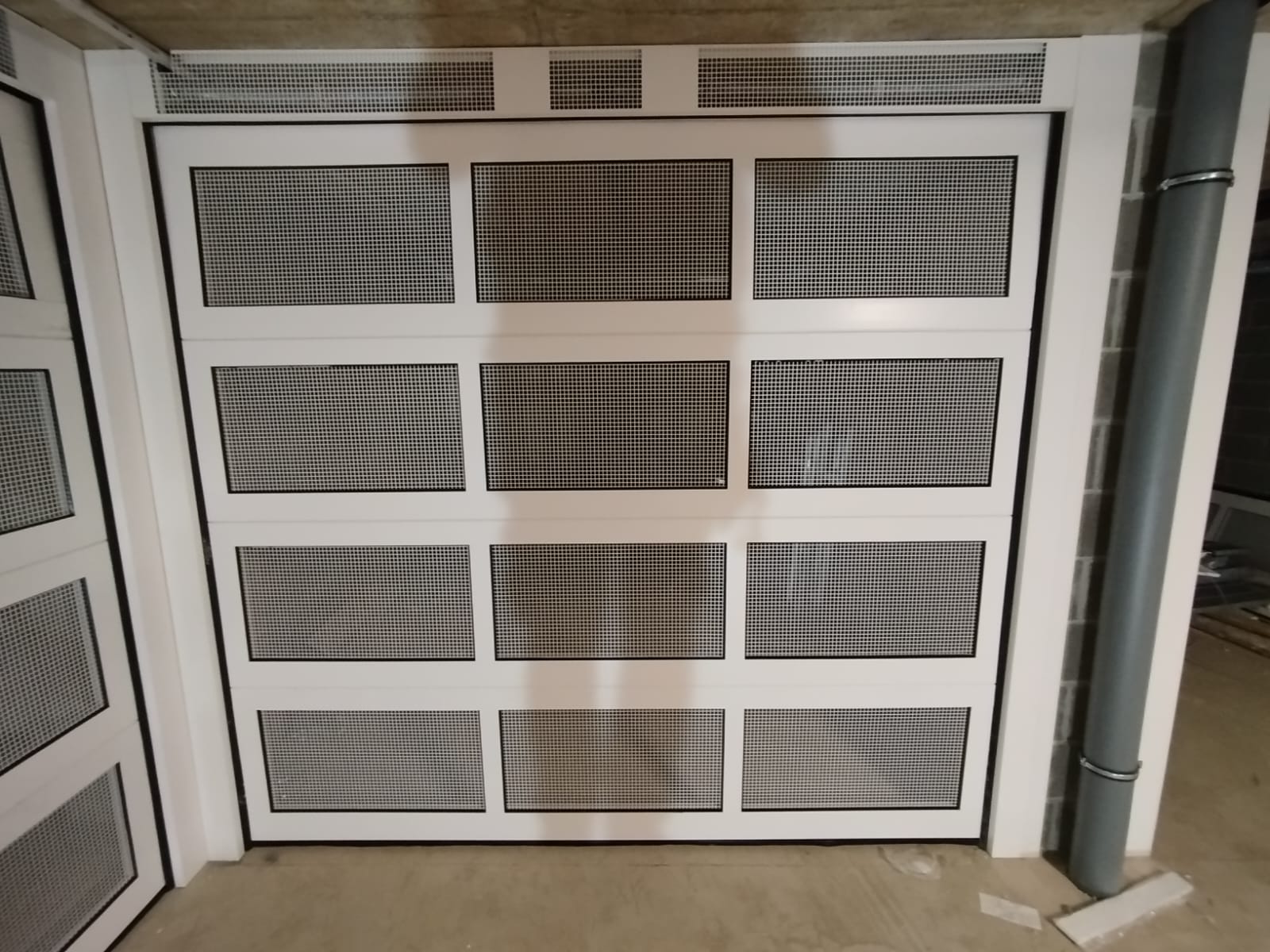 porta sezionale a <p>porte sezionali con veletta areata, maniglia di sollevamento, fotocellule, lampeggiante e pannello retato. RAL 9010 </p>