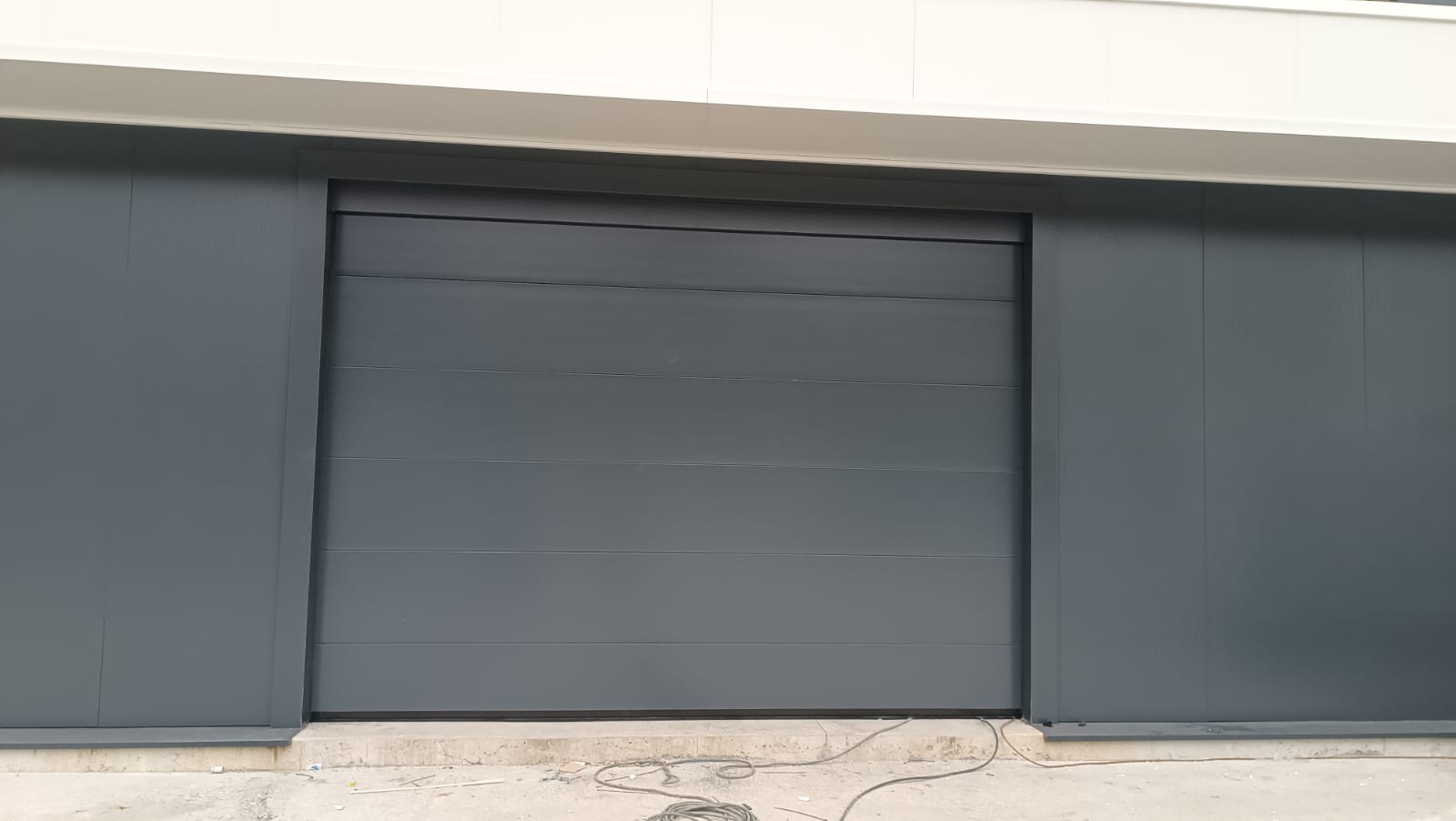 porta sezionale a <p>porta sezionale oltre luce, con pannello intero. RAL 7016</p>